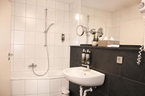 a white bathroom with a sink and a shower at Hotel am Hirschgarten in Filderstadt