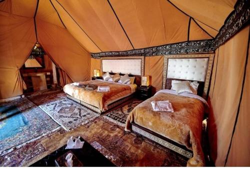a bedroom with two beds in a tent at Maison Riad Tamarighte in Merzouga