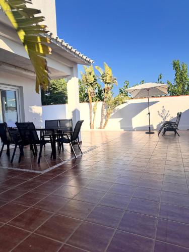 a patio with chairs and tables and an umbrella at Casa Benicasim in Benicàssim