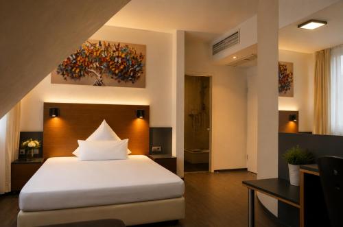 a bedroom with a white bed and a painting on the wall at Hotel am Hirschgarten in Filderstadt