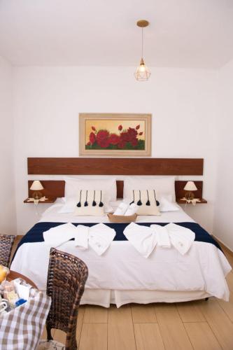 a bedroom with a large bed with white sheets at Pousada Medeiros in Monte Verde