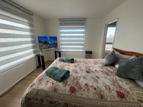 a bedroom with a bed and two windows with blinds at La Casita Austral in Punta Arenas