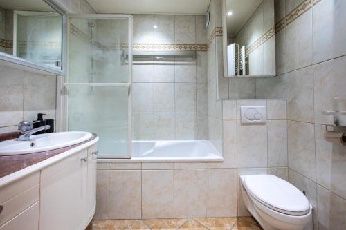 a bathroom with a tub and a toilet and a sink at Blāck diamond spa in Mulhouse