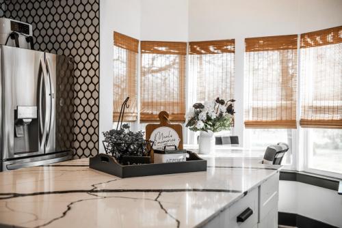 a kitchen with white counters and windows with plants at Made with Love in Thackerville