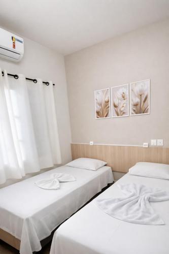 two beds in a room with white walls at Hotel Triangulo Itai in Itaí