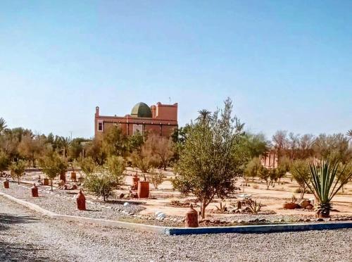 a building in the middle of a desert with trees at Les jardins bleus in Taroudant