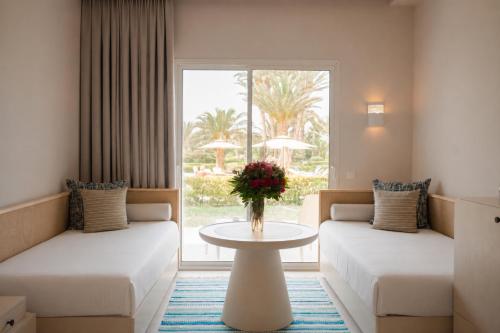 a hotel room with two couches and a table with flowers at Seabel Rym Beach Djerba in Taguermess