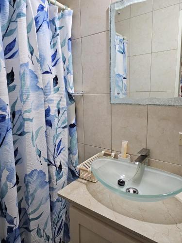 a bathroom sink with a blue and white shower curtain at Riseland Breeze Collection in Carnbee Village