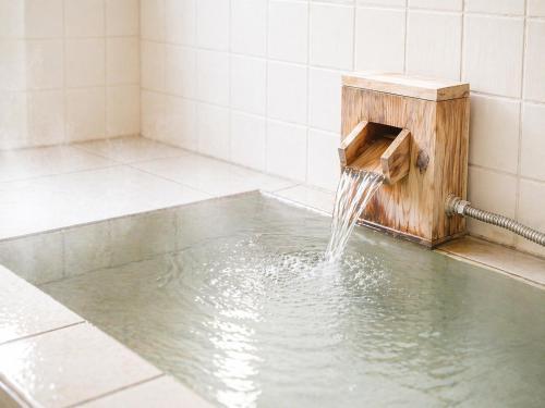 a shower with water coming out of a wooden box at Prirate Villa Naru in Shiraoi