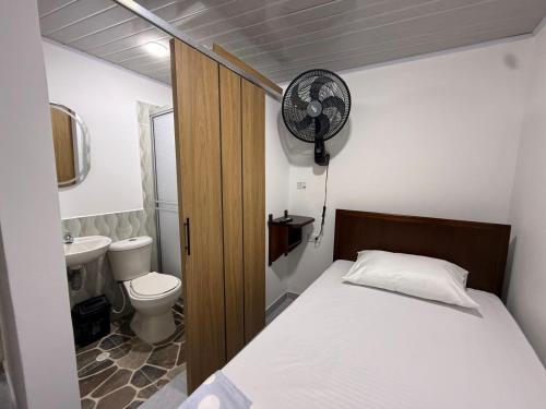 a bedroom with a bed and a toilet and a fan at Hostal Ruta Cafetera in La Tebaida