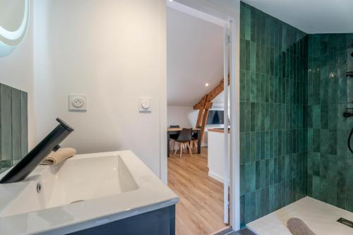 a bathroom with a sink and a green tile wall at L'Emeraude By Clem in Pélussin