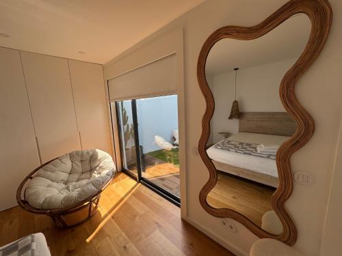 a bedroom with a mirror with a bed and a chair at Sea Breeze - Espinho Beach in Espinho