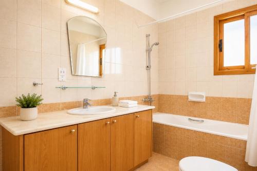 a bathroom with a sink and a tub and a toilet at Villa Chrisandria in Argaka