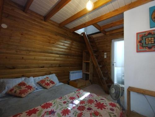a bedroom with a bed in a wooden cabin at Cabañas Ananda in Villa Ventana