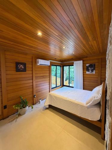 a bedroom with a bed and a wooden ceiling at Chalé das Pedras - Domingos Martins in Domingos Martins