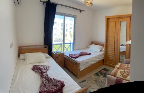 two beds in a room with a window at Mountain View Chalet in Ras El Hekma ماونتن ڤيو رأس الحكمة in Ras Elhekma