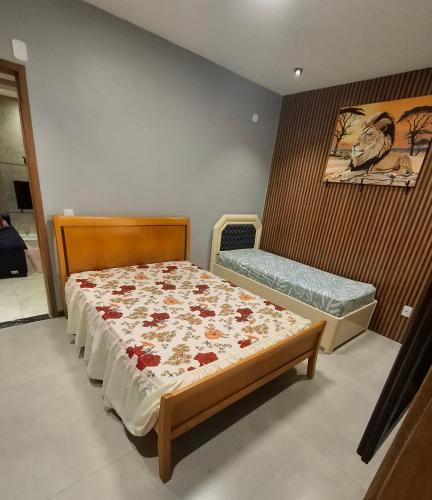 a small bedroom with a bed with a flowery comforter at Casa no centro de Guapimirim, ar condicionado, piscina, churrasqueira, tranquilidade in Guapimirim