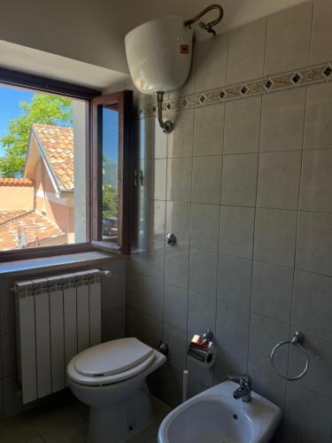 a bathroom with a toilet and a sink and a window at Casa Bellini in Gallinaro