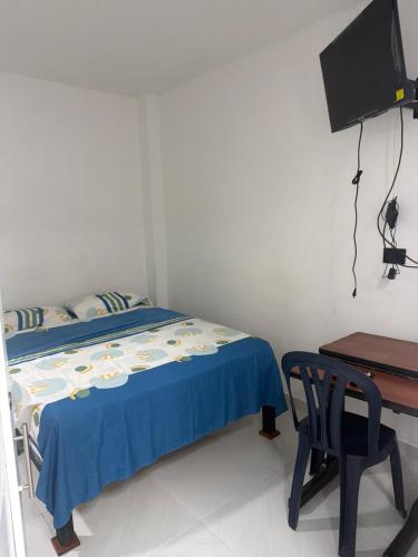 a bedroom with a bed and a desk and a television at Hotel Azulado - Como el mar in Jamundí