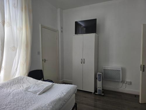 a bedroom with a bed and a cabinet with a television at Spacious Studio on Wood Lane in London