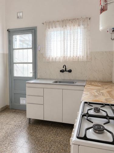 a white kitchen with a stove and a sink at Alojamiento Uruguay in Santa Rosa