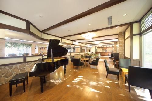 a restaurant with a piano and chairs and a bar at Choyo Resort Hotel in Kamikawa