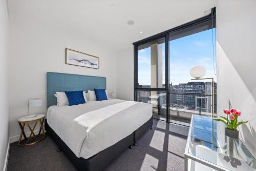 a bedroom with a large bed and a large window at The Eminence Apartments by CLLIX in Melbourne
