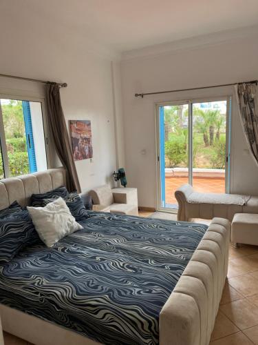 a bedroom with a bed and a couch and windows at Smirpark appartement in M'diq