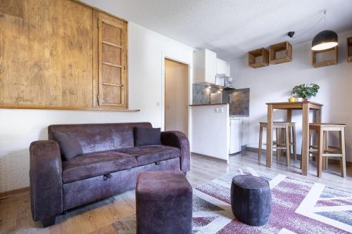 a living room with a couch and a kitchen at Résidence Hôtel Rent - Megève in Megève