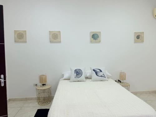 a white bedroom with a white bed with blue pillows at GuestHouse Encanto del Centro 4 in Encarnación