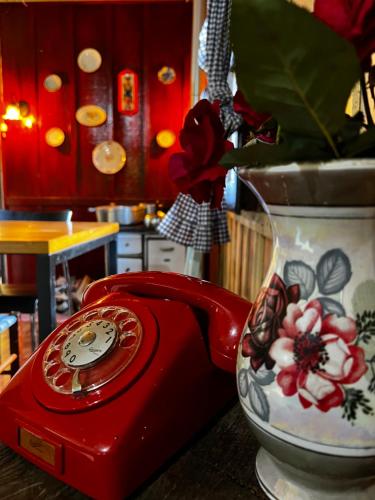 a red phone sitting next to a vase at Casa Centenária com 20 min de Gramado in Três Coroas