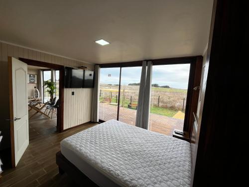a bedroom with a bed and a view of a field at Casa del Sol in Cobquecura