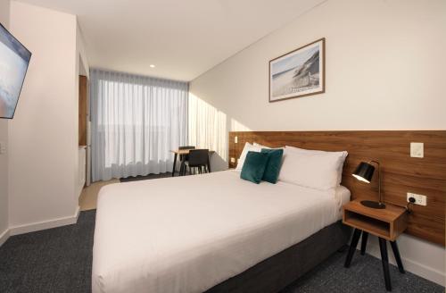 a hotel room with a large bed and a table at Durham Serviced Apartments in Adelaide