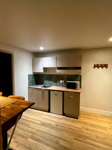 a kitchen with white cabinets and a wooden floor at Cozy studio in Millières