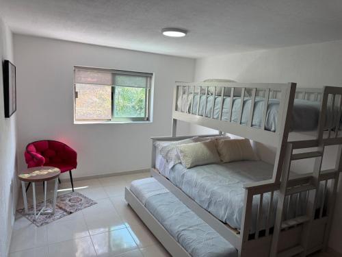 a bedroom with a bunk bed and a red chair at Casa Lomas Guadalajara Jalisco in Lomas de Santa Anita