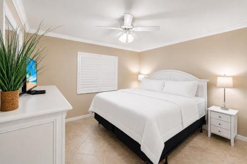 a bedroom with a white bed and a ceiling fan at Waterfront Island Oasis! Heated Pool with Stunning View & 2 Full Bath in Marco Island
