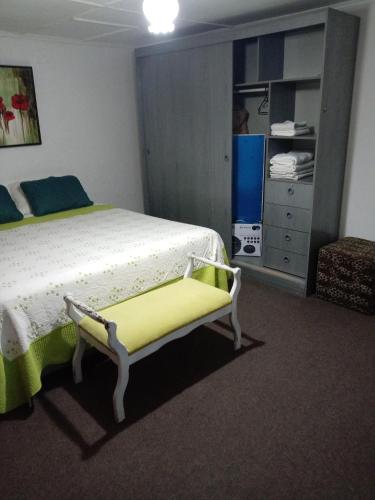 a bedroom with a bed and a yellow bench at Casa in Santiago