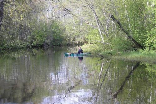a man is sitting in a boat on a river at Lonni Nature Eco-Accommodation in Hagudi