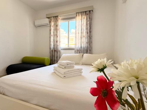 a bedroom with a white bed with a red flower on it at Cozy holyday apartament in Paralimni