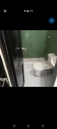 a bathroom with a toilet and a green wall at El delfín Santa Elena -Salinas in Santa Elena