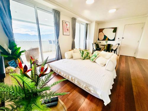 a living room with a white couch and a large window at Prime CBD High Rise Apartment in Cairns