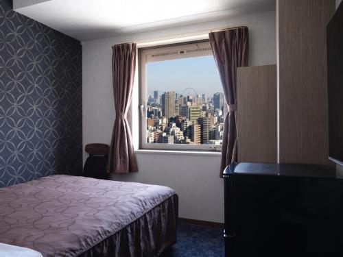 a hotel room with a bed and a window at Swanky Hotel Otomo in Sapporo