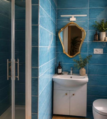 a blue tiled bathroom with a sink and a mirror at Grand gîte convivial proche de Dijon in Marey-sur-Tille