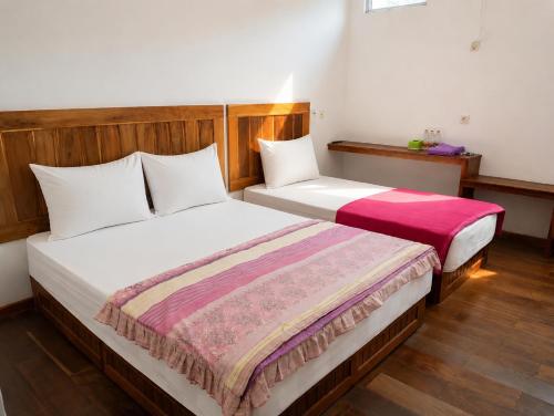 two beds in a hotel room with at Tanjung Inn in Wonosari