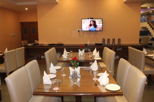 a dining room with a long table and a television at Rama Trident, Katra in Katra