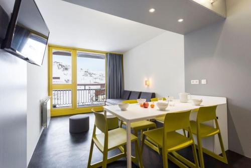 a dining room with a white table and yellow chairs at Résidence LE VARET - ARC 2000 - Ski-in Ski-out in Bourg-Saint-Maurice