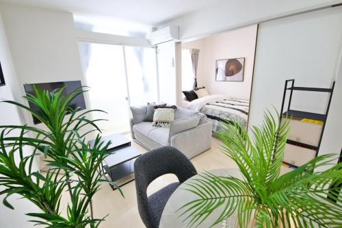 a living room with plants and a couch and a bed at Green Gables B棟 108 in Toyama