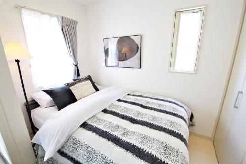 a bedroom with a bed with a black and white blanket at Green Gables B棟 108 in Toyama