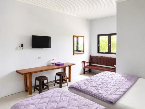 a bedroom with a bed and a desk and a television at Tanjung Inn in Wonosari