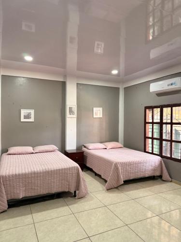 two beds in a room with pink pillows at La Casona Guest House in La Unión